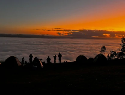 Foto da silhueta de pessoas à beira da Serra do Manecão ao pôr do sol