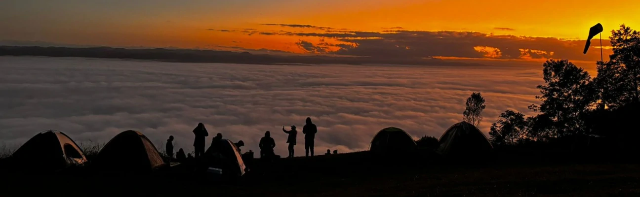 Foto da silhueta de pessoas à beira da Serra do Manecão ao pôr do sol