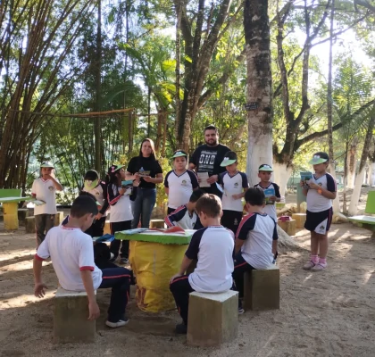 Alunos reunidos em um gramado ouvindo atentamente à explanação do palestrante