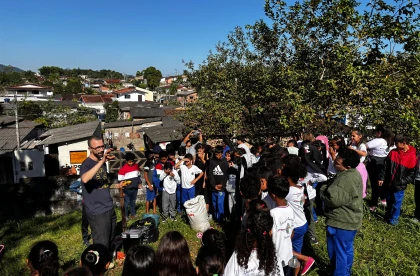 Alunos reunidos em um gramado ouvindo atentamente à explanação do palestrante