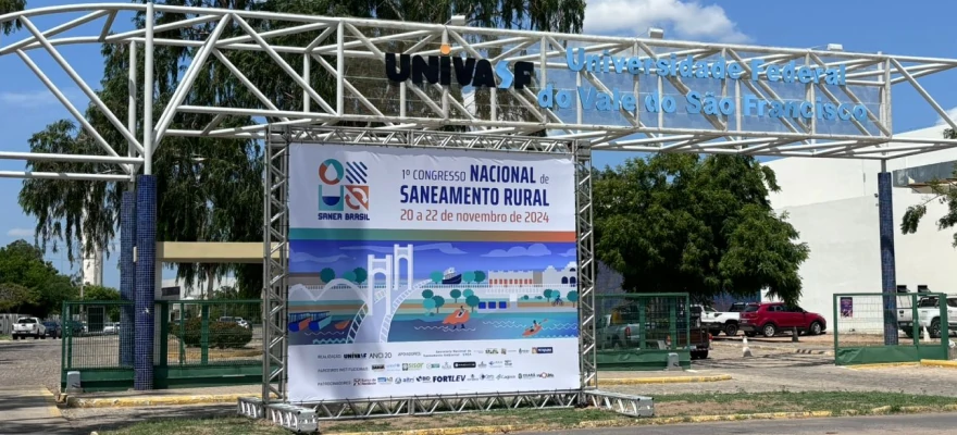 Fachada do local do evento com um banner grande contendo a arte