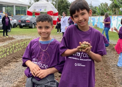 Foto de duas crianças, sorrindo, e a que está à direita está com um sapo nas mãos