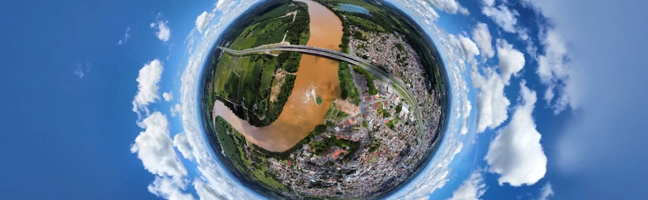 Foto tirada por um dronede um rio de águas turvas e uma ponte e uma cidade ao fundo