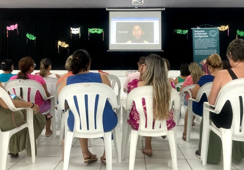 Alunos sentados em suas cadeiras, olhando atentamente o telão