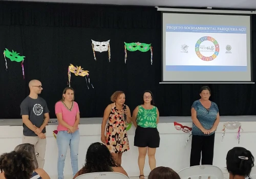 Professor e alguns alunos a frente, na sala de aula